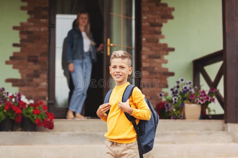 Mom, standing at the door near her house, escorts her son to school, back to school