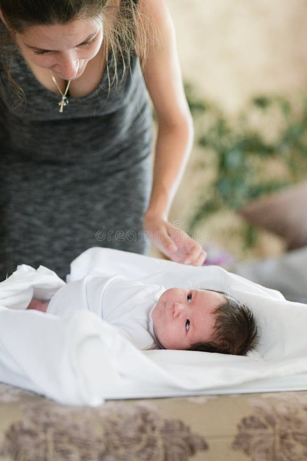 Mom swaddles the baby. A woman is swaddling a small child on the couch. The kid laughs fun. The woman also smiles. They are in a. Mom swaddles the baby. A women royalty free stock images Mom swaddles the baby. A woman is swaddling a small child on the couch. The kid laughs fun. The woman also smiles. They are in a. Mom swaddles the baby. A women royalty free stock images