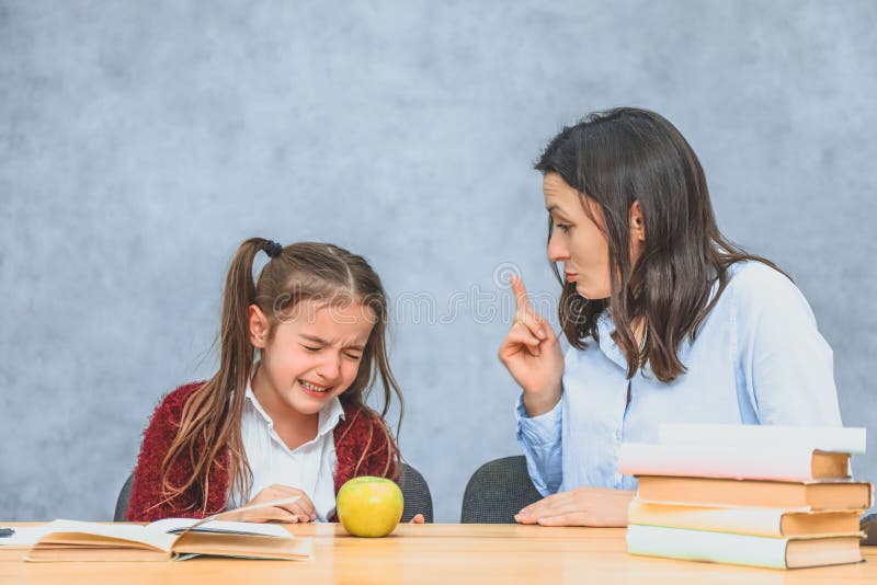 Mom talking to her baby. During this on a gray background. The girl cries when her mother welds her. Gray background. royalty free stock photography Mom talking to her baby. During this on a gray background. The girl cries when her mother welds her. Gray background. royalty free stock photography