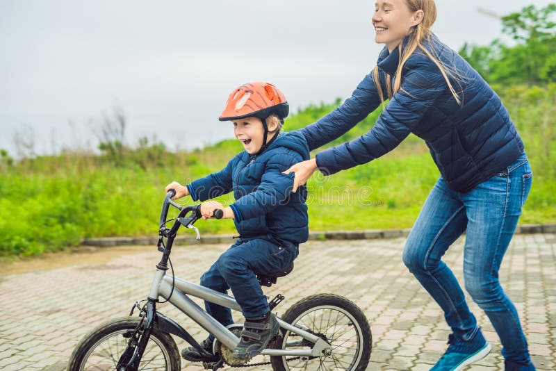 Mom Teaches Son To Ride a Bike in the Park Stock Photo