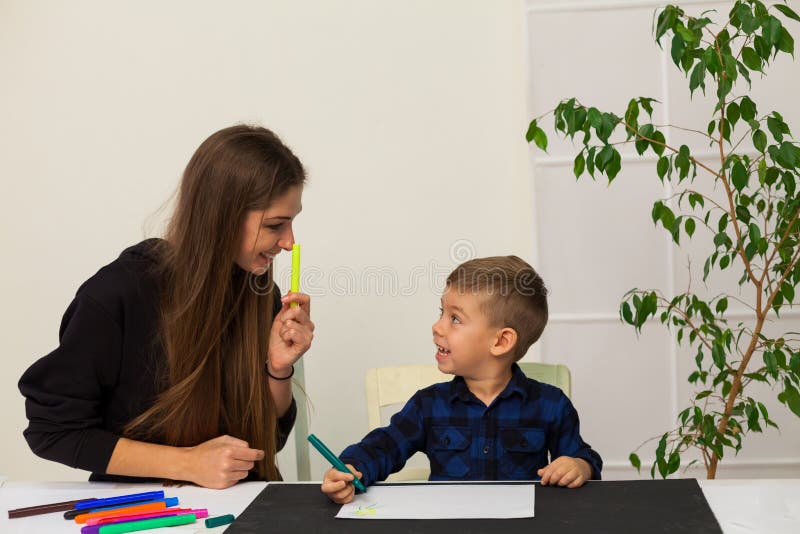 Mom Teaches Young Boy Son To Draw Markers At The Table Stock Image
