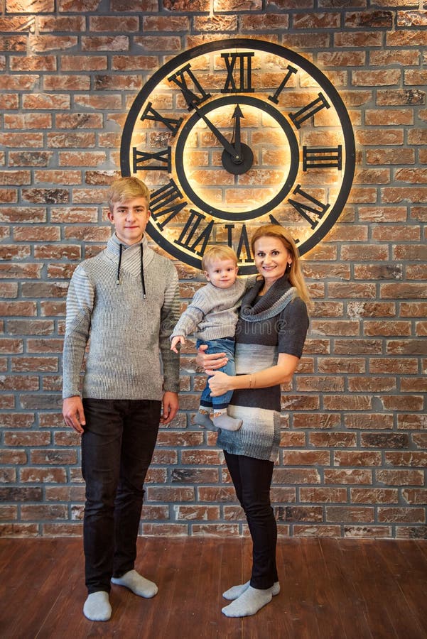 Mom and two sons a teenager and toddler stand near the huge clock 5 minutes before midnight Christmas