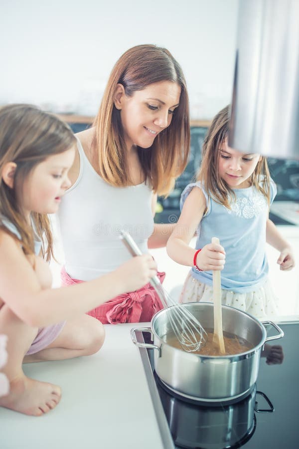 Mom με δύο νέες κόρες διδύμων στα μαγειρεύοντας μακαρόνια κουζινών στοκ φωτογραφία με δικαίωμα ελεύθερης χρήσης Mom με δύο νέες κόρες διδύμων στα μαγειρεύοντας μακαρόνια κουζινών στοκ φωτογραφία με δικαίωμα ελεύθερης χρήσης
