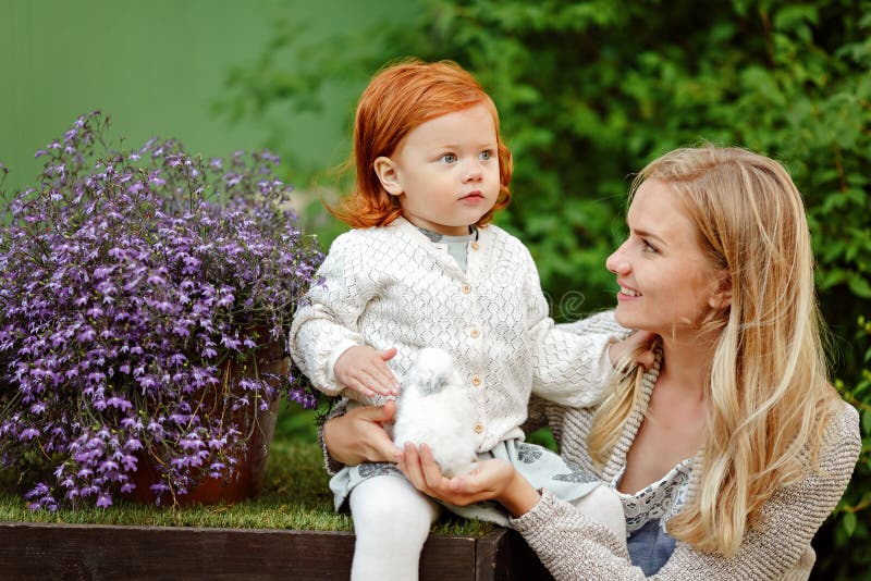 Mom και κοκκινομάλλης κόρη που κρατούν ένα κουνέλι το καλοκαίρι στο θόριο στοκ εικόνα με δικαίωμα ελεύθερης χρήσης