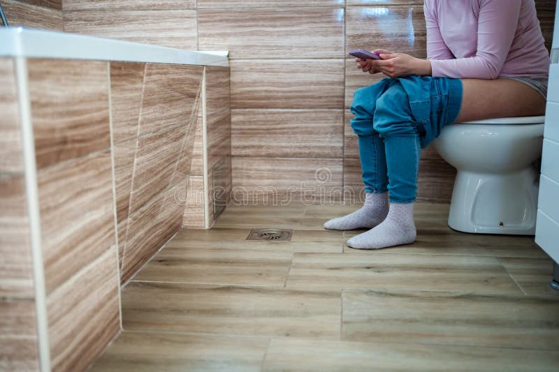 Moment de détente sur la toilette avec téléphone dans la salle de bain calme images libres de droits