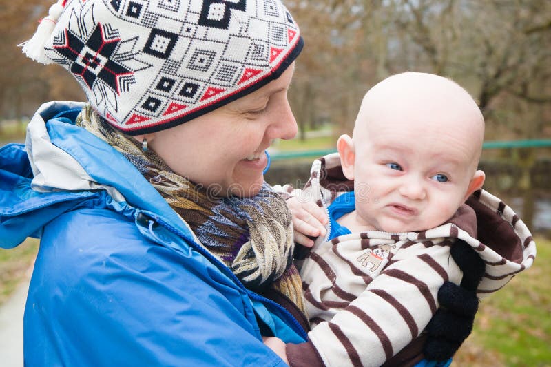 A mother holding her cranky young son outside wearing warm clothes on a cold day enjoying the fresh air. A mother holding her cranky young son outside wearing warm clothes on a cold day enjoying the fresh air.