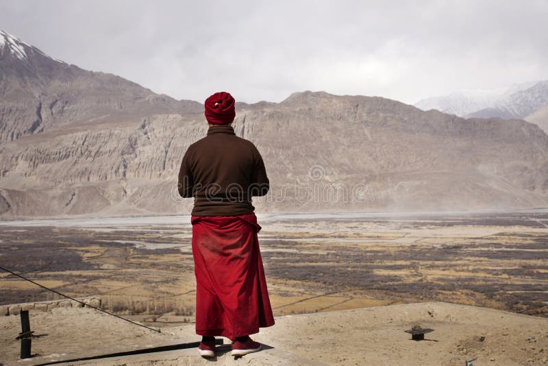 Monaci tibetani in pellegrinaggio si affacciano sul monastero del dirupo Galdan Tashi Chuling Gompa, in vista nel villaggio di Hu fotografia stock