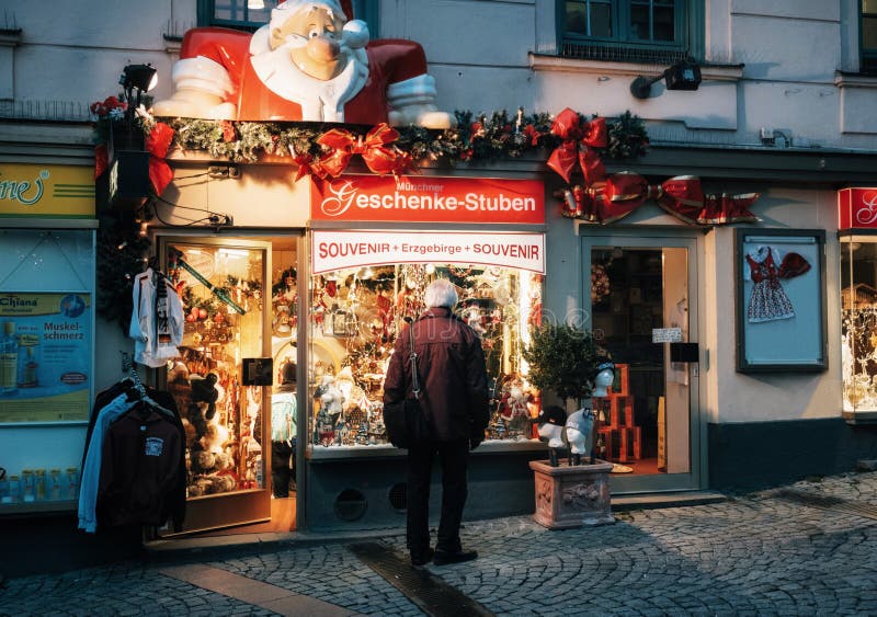 Monaco di Baviera, sguardi dell'uomo senior alla finestra del negozio sulla notte di Natale immagine stock Monaco di Baviera, sguardi dell'uomo senior alla finestra del negozio sulla notte di Natale immagine stock