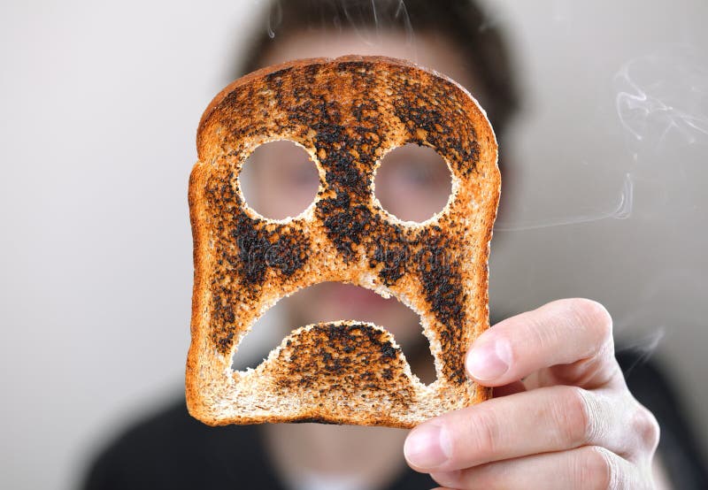 L'uomo con in mano una bruciato fetta di pane tostato con un infelice smiley conept per il brutto inizio di giornata.