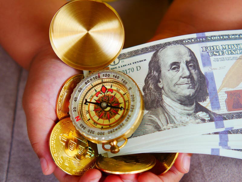 Moneta in dollari e bussola d'oro nelle mani delle ragazze. immagini stock