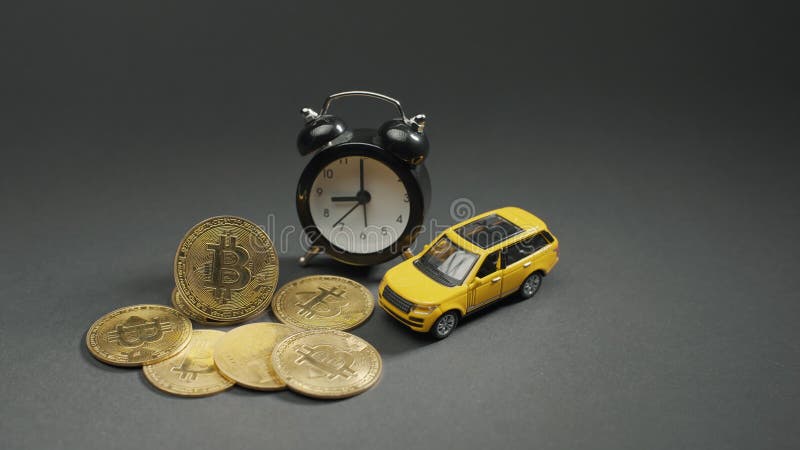 Moneta kryptograficzna bitcoina na szarej tablicy z żółtym samochodem i oglądać makro. koncepcja połowy i wydobycia bitcoina