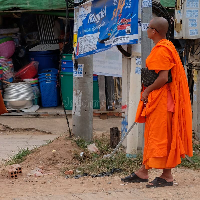 Cambodia, Siem Reap 12/08/2018 Buddhist monk in orange robes near an advertising banner on the street. Cambodia, Siem Reap 12/08/2018 Buddhist monk in orange robes near an advertising banner on the street