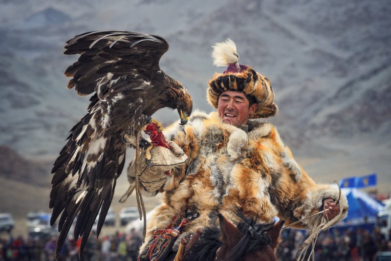 Mongolia. Traditional Golden Eagle Festival. Unknown Mongolian Hunter Berkutchi On Horse With Golden Eagle. Falconry In West Mongolia.Flying golden eagle. Mongolia. Traditional Golden Eagle Festival. Unknown Mongolian Hunter Berkutchi On Horse With Golden Eagle. Falconry In West Mongolia.Flying golden eagle