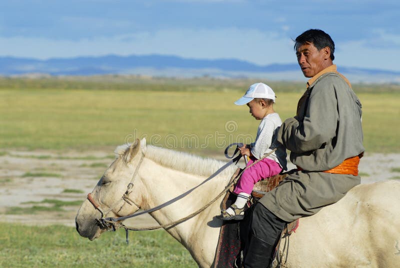 Mongoolse mensenritten op horseback met een jong geitje, Harhorin, Mongolië stock foto's Mongoolse mensenritten op horseback met een jong geitje, Harhorin, Mongolië stock foto's