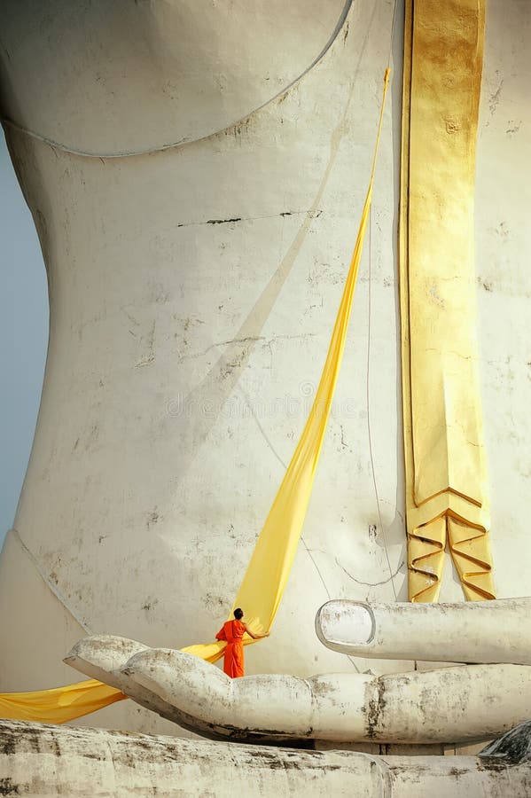 A monk preparing yellow robe for Buddha statue. stock photography A monk preparing yellow robe for Buddha statue. stock photography