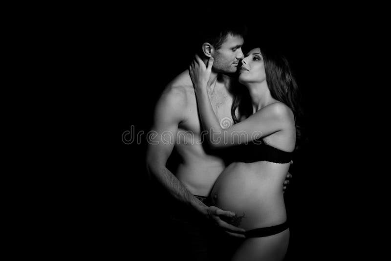 Monochrome portrait of happy loving couple in a moment of love and tenderness. Pregnant women with hands over tummy. Black and white photo. Monochrome portrait of happy loving couple in a moment of love and tenderness. Pregnant women with hands over tummy. Black and white photo