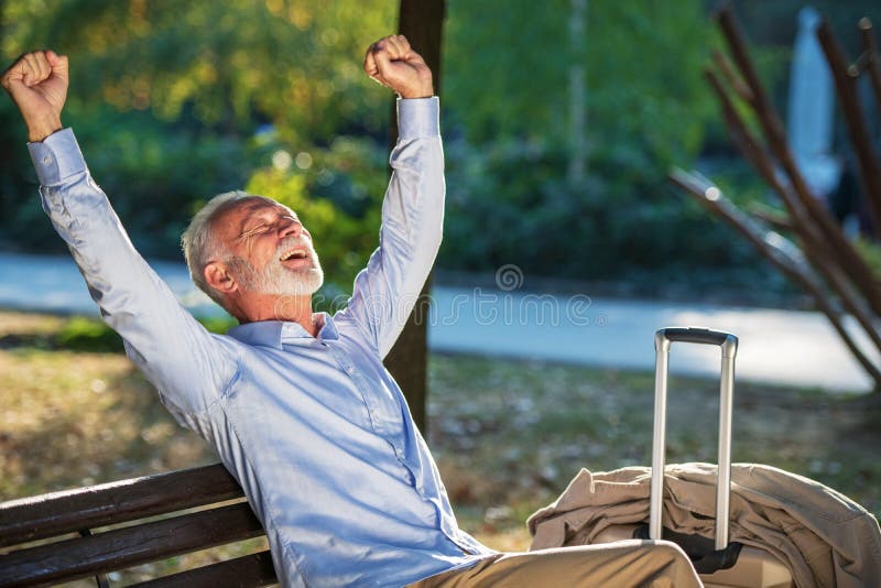Monsieur supérieur s'asseyant sur un banc en bois et détendant en parc images stock Monsieur supérieur s'asseyant sur un banc en bois et détendant en parc images stock