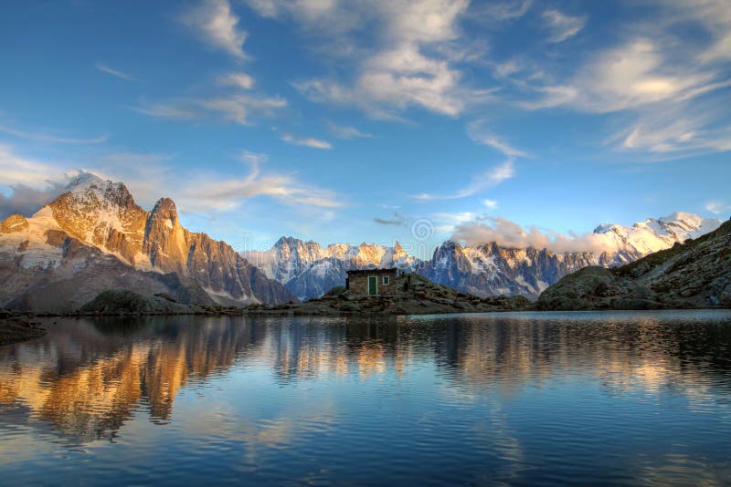 Mont Blanc Massif reflecting in the still waters of Lake Blanc (Lac Blanc) in Massif Aiguilles Rouges above Chamonix, France at sunset. On right the Mont Blanc peak (4808m, the highest mountain in the European Alps), followed by Mont Maudit and Mont Blanc du Tacul; the Aiguille du Midi and the 3 Aigulles de Chamonix; behind the shelter, the Dent du Geant and Grandes Jorasses, while on the left is. Mont Blanc Massif reflecting in the still waters of Lake Blanc (Lac Blanc) in Massif Aiguilles Rouges above Chamonix, France at sunset. On right the Mont Blanc peak (4808m, the highest mountain in the European Alps), followed by Mont Maudit and Mont Blanc du Tacul; the Aiguille du Midi and the 3 Aigulles de Chamonix; behind the shelter, the Dent du Geant and Grandes Jorasses, while on the left is