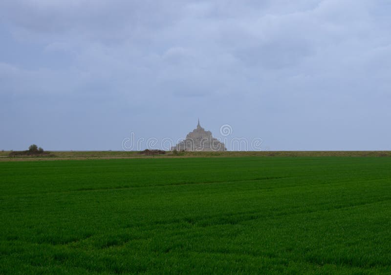 Mont Saint Michel from afar with green farmlands in foreground, Normandy region, France. Mont Saint Michel from afar with green farmlands in foreground, Normandy region, France