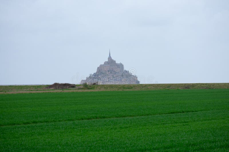 Mont Saint Michel from afar with green farmlands in foreground, Normandy region, France. Mont Saint Michel from afar with green farmlands in foreground, Normandy region, France