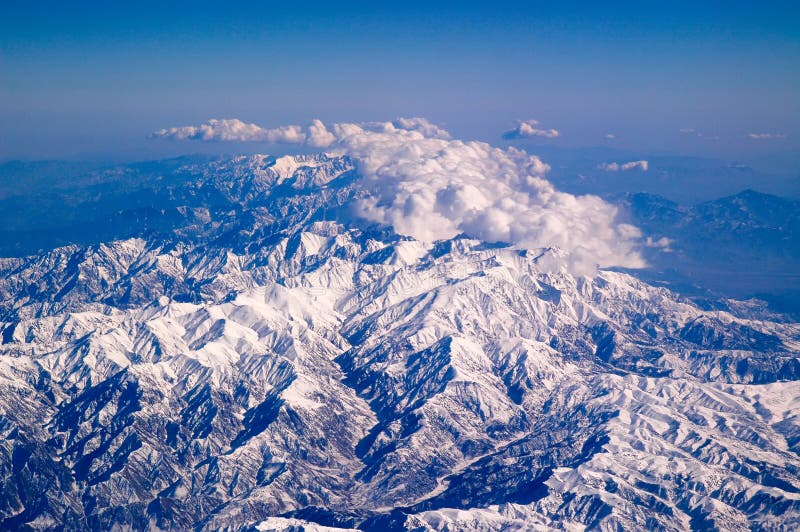 Montagne coperte di neve e di nuvole, vista aerea Superficie del pianeta della terra Viaggiando intorno al mondo ambiente fotografia stock Montagne coperte di neve e di nuvole, vista aerea Superficie del pianeta della terra Viaggiando intorno al mondo ambiente fotografia stock
