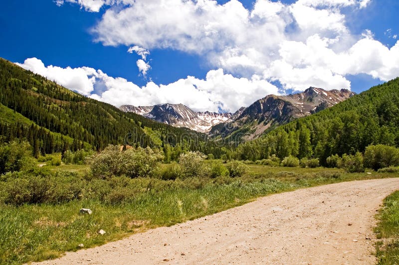 Beautiful Colorado mountains and high white clouds on a dirt road near the end of the valley. Beautiful Colorado mountains and high white clouds on a dirt road near the end of the valley.