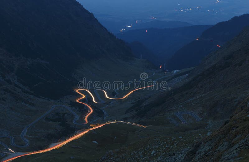 Montanhas de Fagaras em Romênia na noite do verão com a estrada de enrolamento de Transfagarasan com luzes foto de stock Montanhas de Fagaras em Romênia na noite do verão com a estrada de enrolamento de Transfagarasan com luzes foto de stock