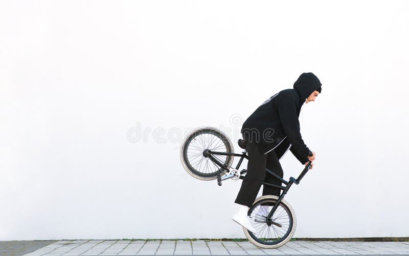 Montar a caballo del jinete de Bmx en una rueda delantera de una bicicleta en un fondo blanco imágenes de archivo libres de regalías