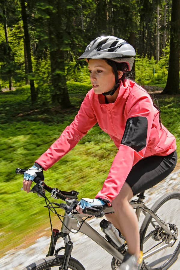 Montaña de la mujer biking en la falta de definición de movimiento del bosque foto de archivo libre de regalías Montaña de la mujer biking en la falta de definición de movimiento del bosque foto de archivo libre de regalías