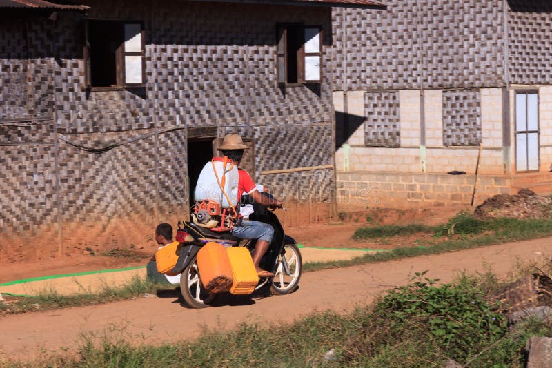 Montañas de Kalaw, Myanmar - 18 de noviembre de 2019: Aldeanos locales que conducen en la moto a través de un pueblo en las monta fotografía de archivo Montañas de Kalaw, Myanmar - 18 de noviembre de 2019: Aldeanos locales que conducen en la moto a través de un pueblo en las monta fotografía de archivo