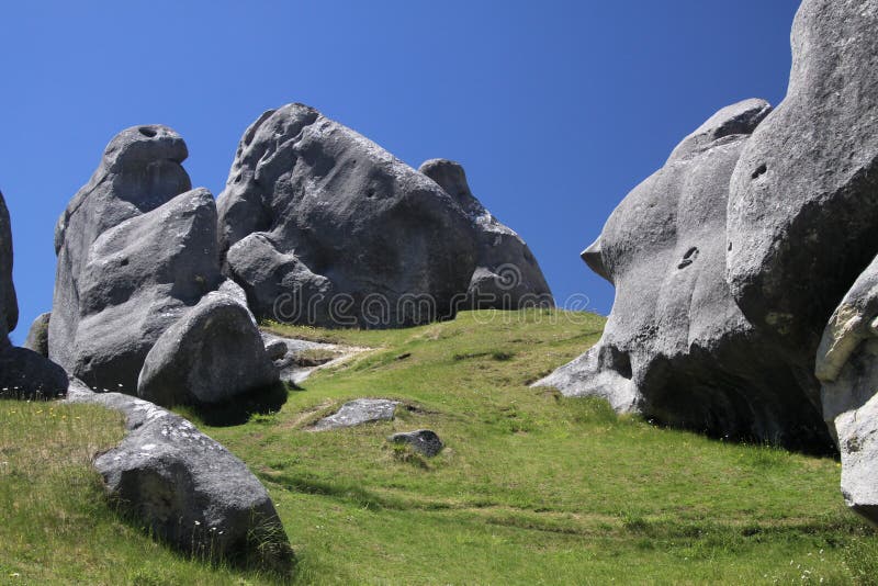 Monte do castelo, Nova Zelândia, ilha sul: Pedregulhos dispersados da pedra calcária em um prado que contrasta com o céu azul sem imagem de stock Monte do castelo, Nova Zelândia, ilha sul: Pedregulhos dispersados da pedra calcária em um prado que contrasta com o céu azul sem imagem de stock
