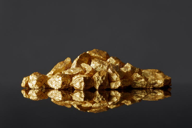 Monticello delle pepite di oro su un fondo di superficie riflettente nero immagine stock libera da diritti Monticello delle pepite di oro su un fondo di superficie riflettente nero immagine stock libera da diritti