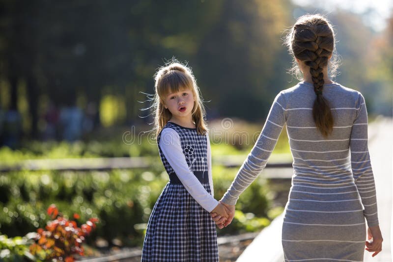 Moody cute child girl holding mother hand looking back on warm day outdoors. Family relationship and recreation royalty free stock photos Moody cute child girl holding mother hand looking back on warm day outdoors. Family relationship and recreation royalty free stock photos