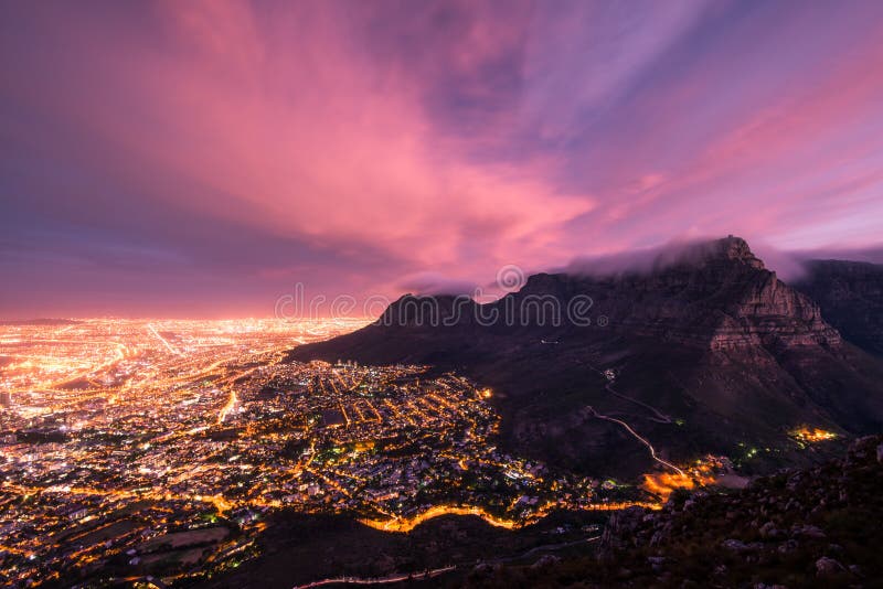 Moody Table Mountain after sunset with city lights as seen from Lions Head. Moody Table Mountain after sunset with city lights as seen from Lions Head.