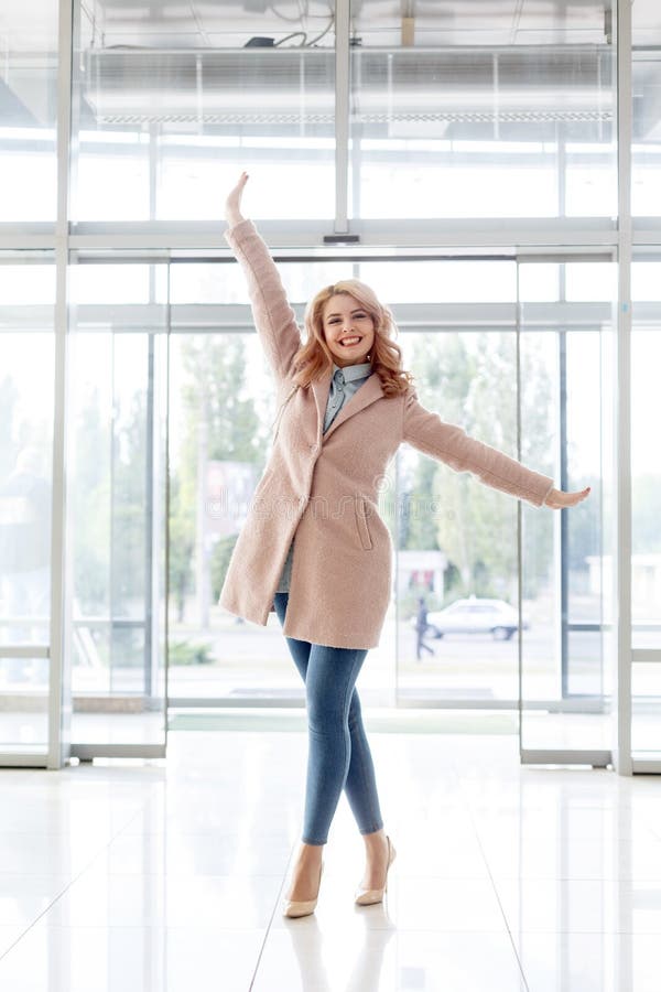 Mooi blond jong meisje in een mooie beige laag, jeans en hoge hielen royalty-vrije stock foto's Mooi blond jong meisje in een mooie beige laag, jeans en hoge hielen royalty-vrije stock foto's