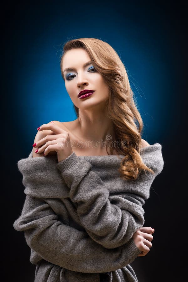 Mooi blond meisje die een grijze sweater met een elegant haar dragen royalty-vrije stock afbeelding Mooi blond meisje die een grijze sweater met een elegant haar dragen royalty-vrije stock afbeelding