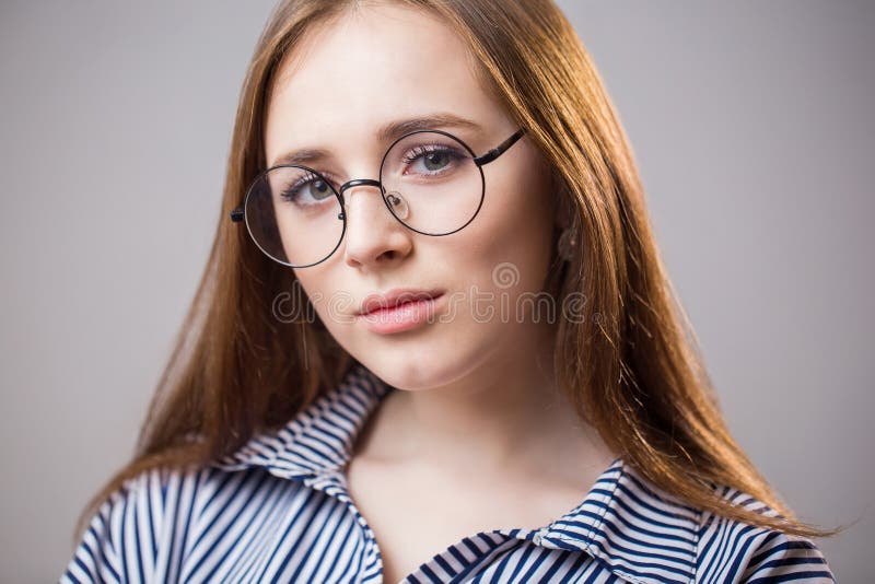 Mooi close-upportret van een jong studentenmeisje die glazen op een grijze achtergrond dragen Aantrekkelijke roodharigevrouw met royalty-vrije stock fotografie Mooi close-upportret van een jong studentenmeisje die glazen op een grijze achtergrond dragen Aantrekkelijke roodharigevrouw met royalty-vrije stock fotografie