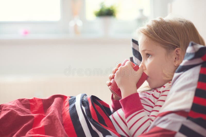 Mooi drinkt weinig kindmeisje die in bed leggen en thee royalty-vrije stock fotografie Mooi drinkt weinig kindmeisje die in bed leggen en thee royalty-vrije stock fotografie