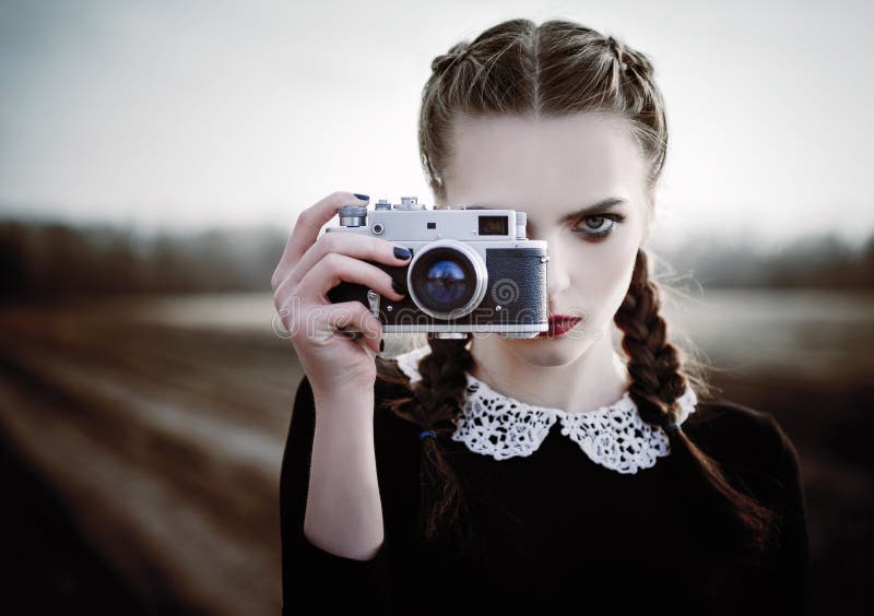 Mooi droevig jong meisje die op uitstekende filmcamera fotograferen Close-up openluchtportret royalty-vrije stock fotografie Mooi droevig jong meisje die op uitstekende filmcamera fotograferen Close-up openluchtportret royalty-vrije stock fotografie