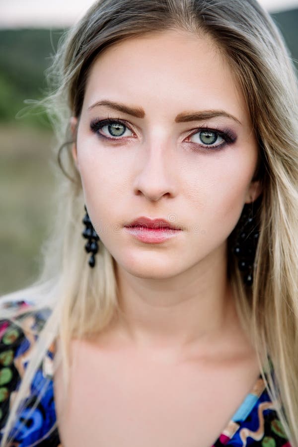 Mooi dromerig blondemeisje met blauwe ogen in een lichte turkooise kleding die op de stenen liggen stock afbeelding Mooi dromerig blondemeisje met blauwe ogen in een lichte turkooise kleding die op de stenen liggen stock afbeelding