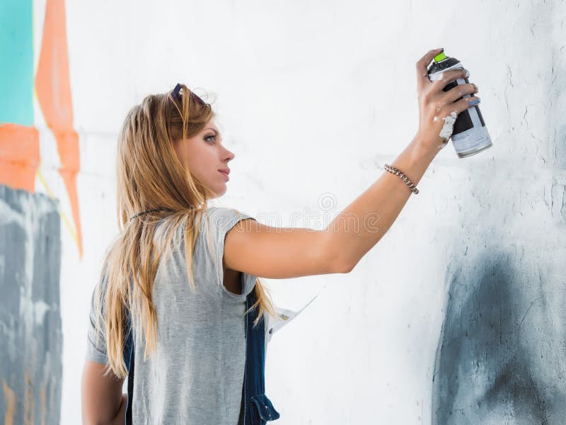 Mooi Jong Blondemeisje die graffiti van groot oog met aërosolnevel maken op stedelijke straatmuur Creatief art begaafd royalty-vrije stock afbeelding Mooi Jong Blondemeisje die graffiti van groot oog met aërosolnevel maken op stedelijke straatmuur Creatief art begaafd royalty-vrije stock afbeelding