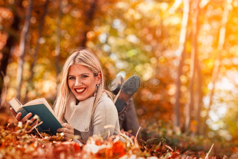 Mooi jong meisje die een boek in de herfstpark lezen royalty-vrije stock afbeelding Mooi jong meisje die een boek in de herfstpark lezen royalty-vrije stock afbeelding
