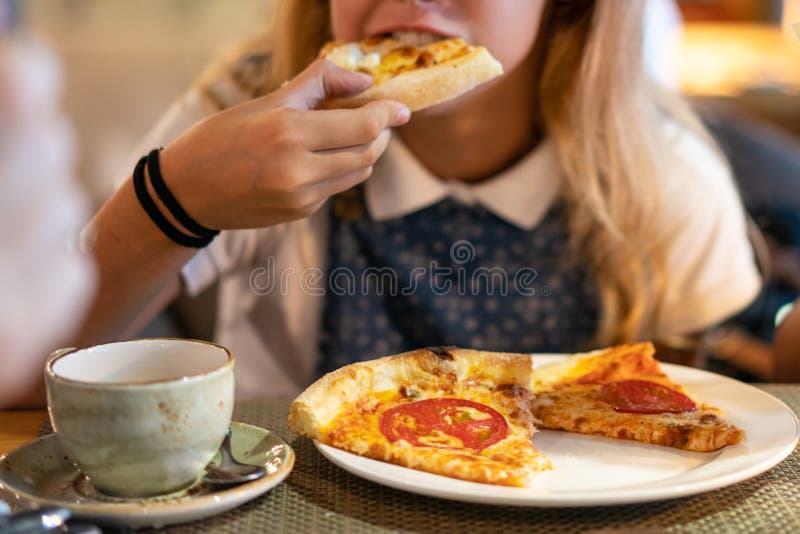 Mooi jong meisje die een plak van pizza eten stock foto Mooi jong meisje die een plak van pizza eten stock foto