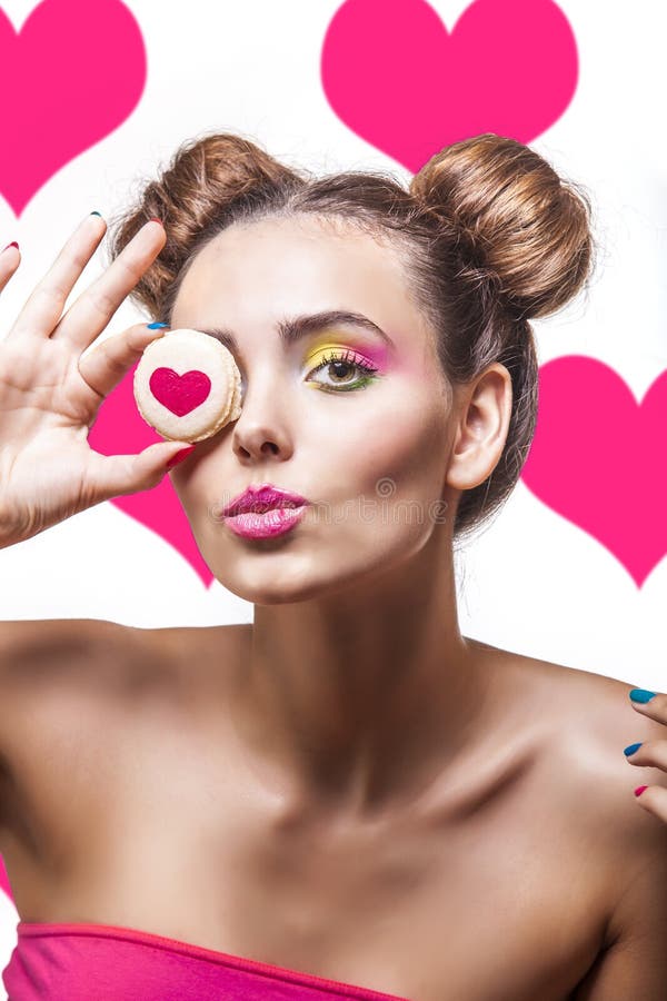 Mooi mannequinmeisje met koekjes met harten op roze bedelaars stock foto Mooi mannequinmeisje met koekjes met harten op roze bedelaars stock foto