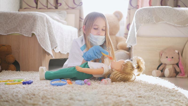 Mooi meisje dat dokters speelt met pop thuis.