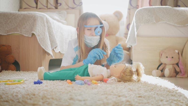 Mooi meisje dat dokters speelt met pop thuis.