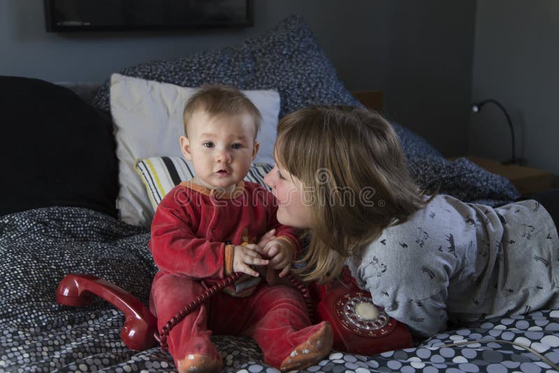 Mooi meisje die op bed liggen die veel liefs haar leuke mollige babyzuster bekijken royalty-vrije stock foto's Mooi meisje die op bed liggen die veel liefs haar leuke mollige babyzuster bekijken royalty-vrije stock foto's