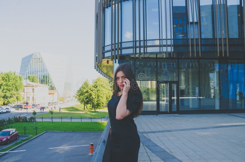 Mooi meisje die op de telefoon dichtbij commercieel centrum spreken royalty-vrije stock foto's Mooi meisje die op de telefoon dichtbij commercieel centrum spreken royalty-vrije stock foto's