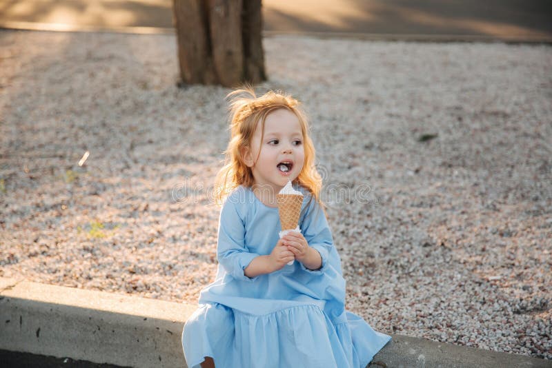 Mooi meisje in een blauwe kleding die een roomijs eten stock foto Mooi meisje in een blauwe kleding die een roomijs eten stock foto
