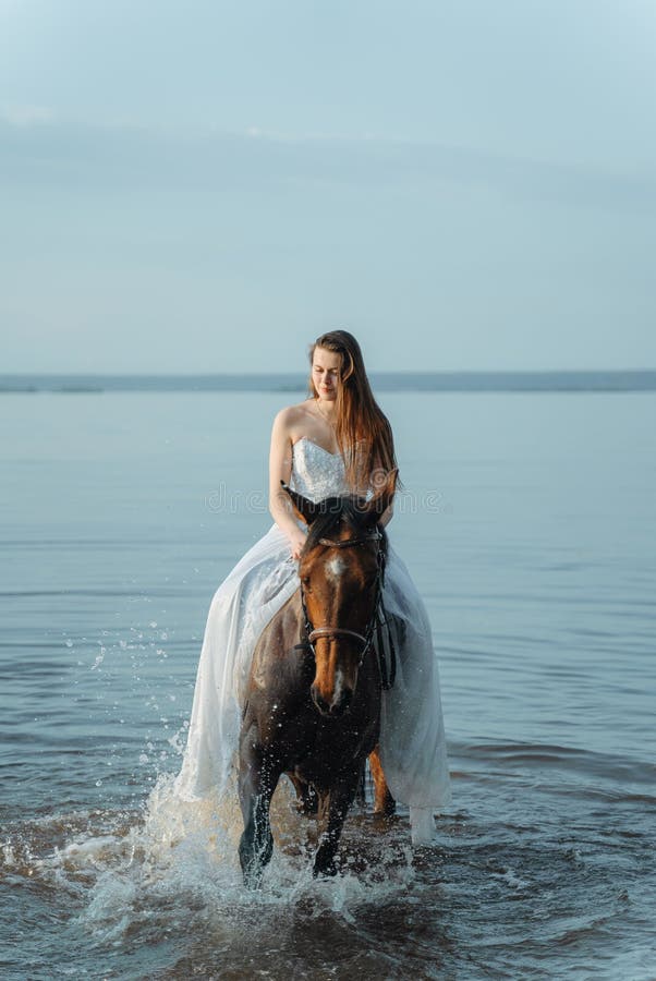 Mooi meisje in een witte lange kleding die een paard berijden Bruid in het meer op horseback royalty-vrije stock foto Mooi meisje in een witte lange kleding die een paard berijden Bruid in het meer op horseback royalty-vrije stock foto